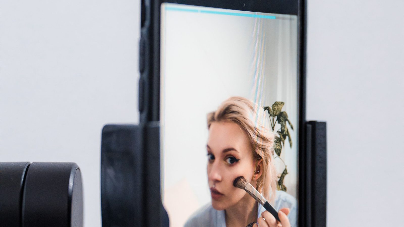 A phone on a tripod films a creator testing a cosmetic