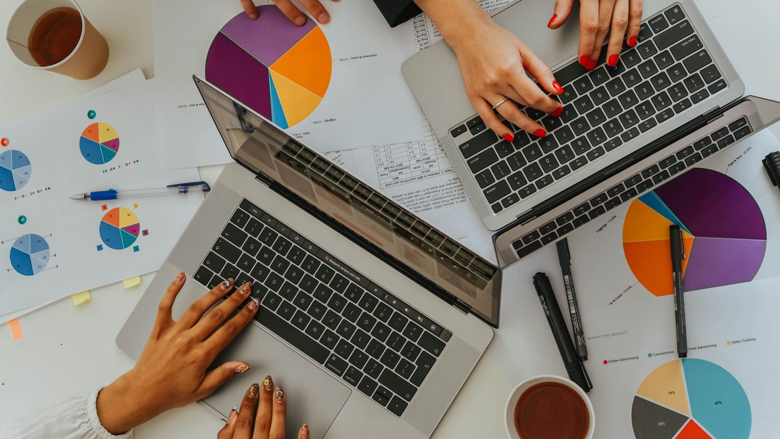 Hands beside laptops and printed charts