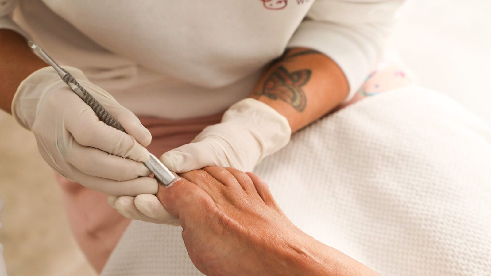 Odsuwanie skórek metalowym narzędziem podczas manicure